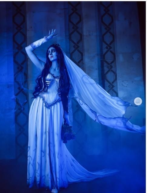 Misty cool blue studio full-body shot of @bellatrixaiden, dynamic raised arm pose showcasing long sheer printed veil floating in air, corset lace neckline and layered chiffon floor-length ghost bridal skirt