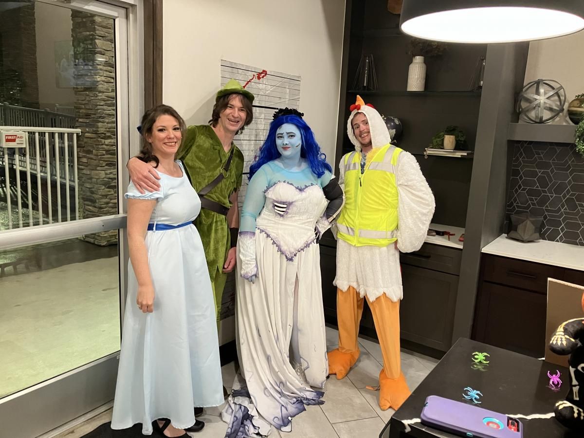 Indoor Halloween group portrait shot of @Jillian surrounded by multiple different theme cosplayers, full Emily ghost bridal cos set including long gradient veil and printed skeleton arm sleeves, holiday decorated kitchen interior background
