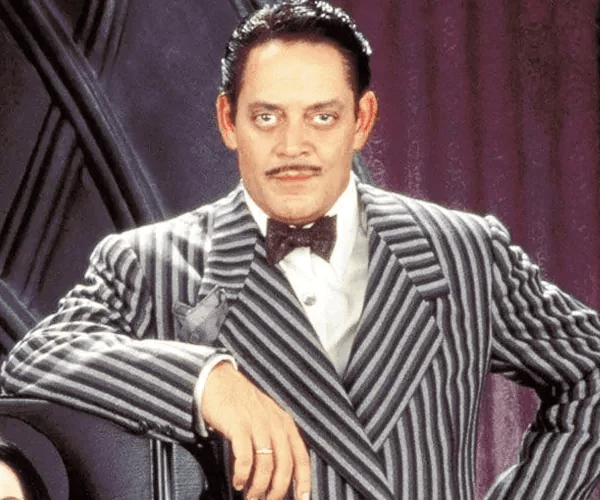 Classic movie still of Gomez Addams, wearing iconic stripe suit and black bow tie
