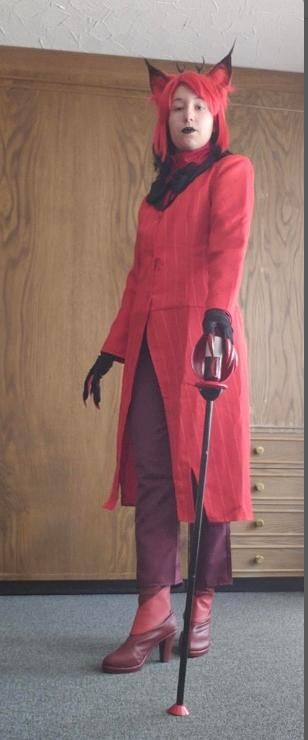 Casual indoor full-body fitting shot against wood panel wall by @yasha.cosplay.place, red pinstripe long coat, maroon trousers, claw gloves, fox ear headpiece, holding radio cane prop, simple home interior scene for daily costume inspection