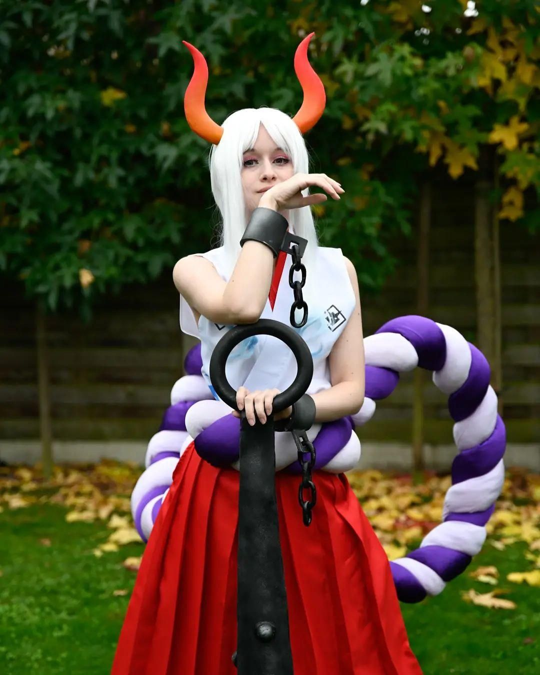 Garden outdoor cosplay shot by @corvus.cosplay as One Piece Yamato, standing pose with kanabo club, shackle chains, horns and large rope prop.