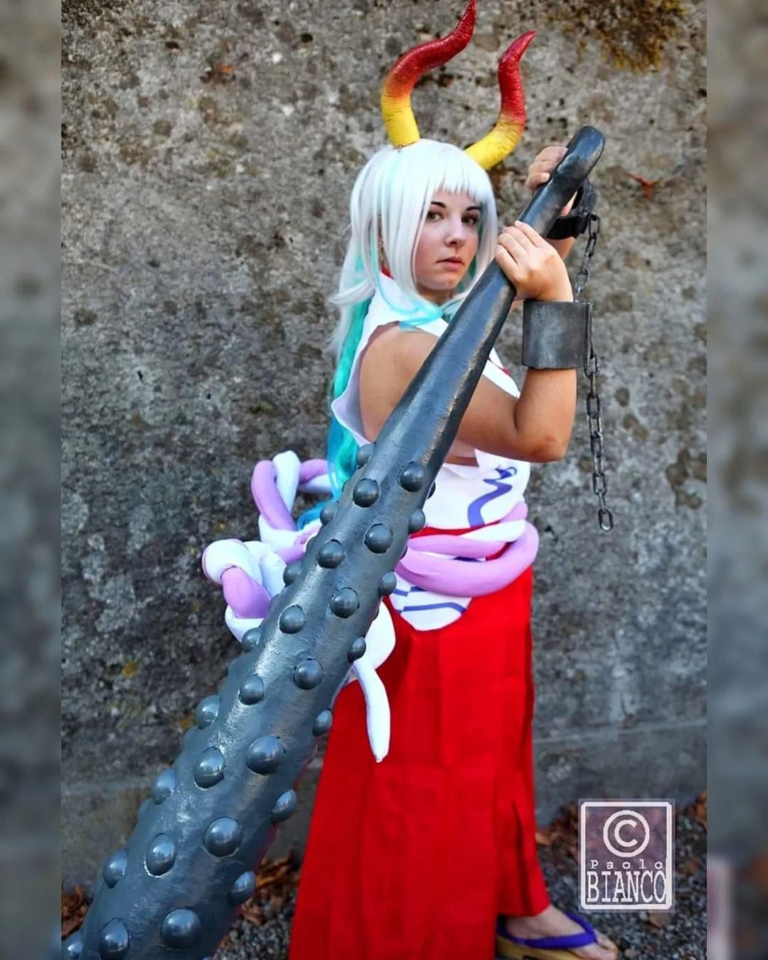 Full‑body outdoor cosplay shot by @GiaDi Rox, One Piece Yamato leaning on huge kanabo club prop, gradient horns and complete costume accessories.