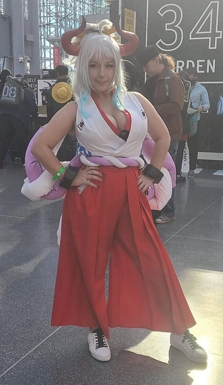 Full‑body convention cosplay by @MyMelo for One Piece Yamato, hands on hips pose, complete outfit with big rope decoration and shackles.