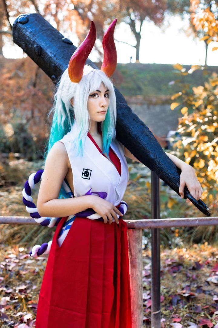 Autumn outdoor cosplay shot by @Teitoku as One Piece Yamato, kanabo club resting on shoulder, red horns, blue‑tip wig and full costume set.