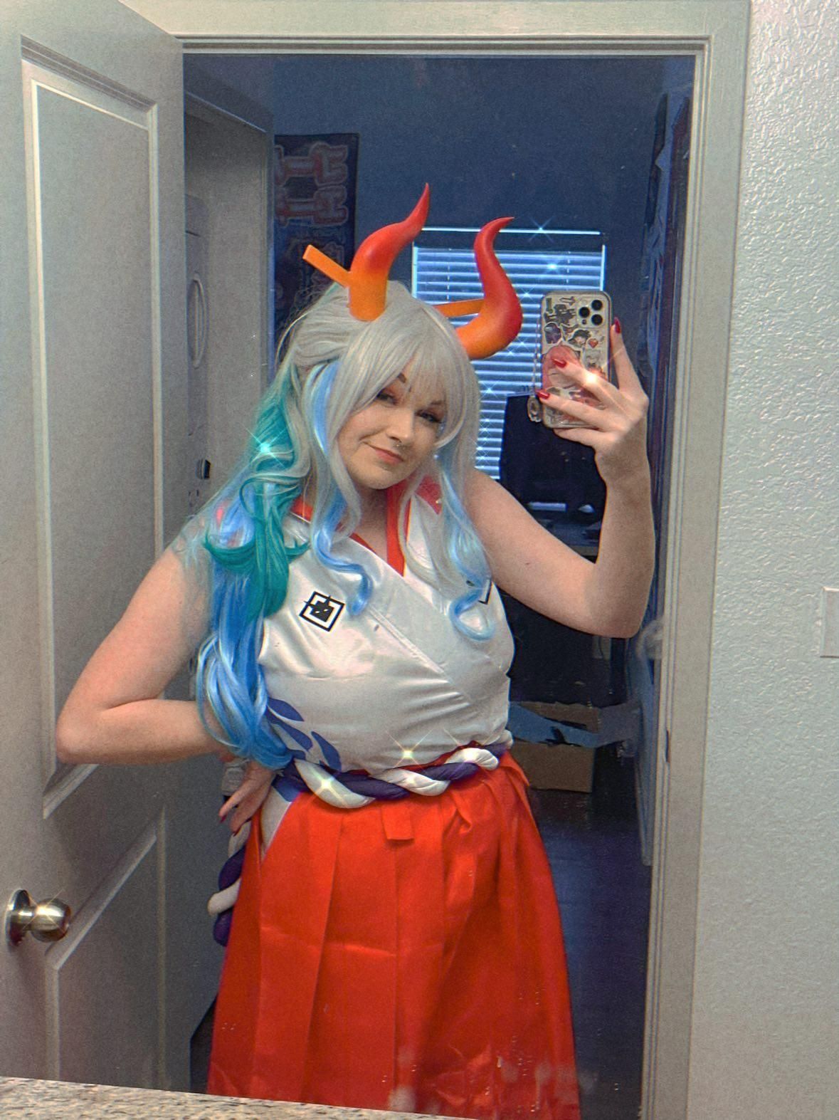 Indoor mirror selfie cosplay shot by @v0dch4n as One Piece Yamato, gradient horns, blue highlighted wig, sleeveless top and twisted rope waist accessory.