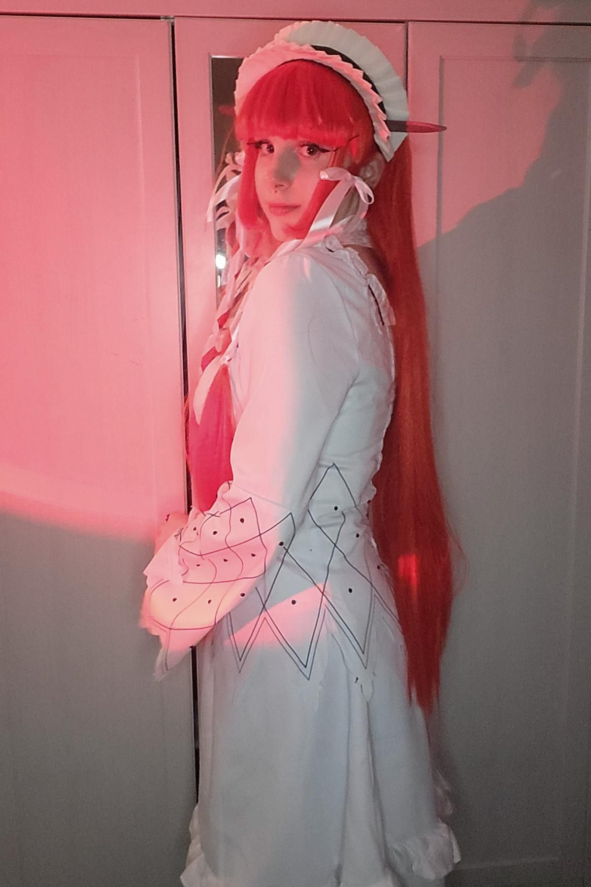 Indoor side profile cosplay photo of Chidori Yoshino worn by customer Seth, showing long red wig effect