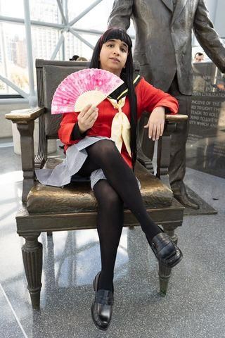 Indoor museum full-body seated customer photo of Yukiko Amagi cosplay, relaxed pose with folding fan