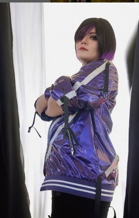 Side view studio customer shot by @iachoku, cross arms pose showing side strap details of Reina’s shiny purple black jacket, gradient purple bob wig, plain curtain backdrop