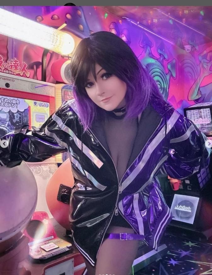 Half-body arcade customer shot by @v0dch4n, forward lean pose beside rhythm game machine, full Reina shiny two-tone jacket, black choker, gradient purple long wig, colorful cartoon mural backdrop