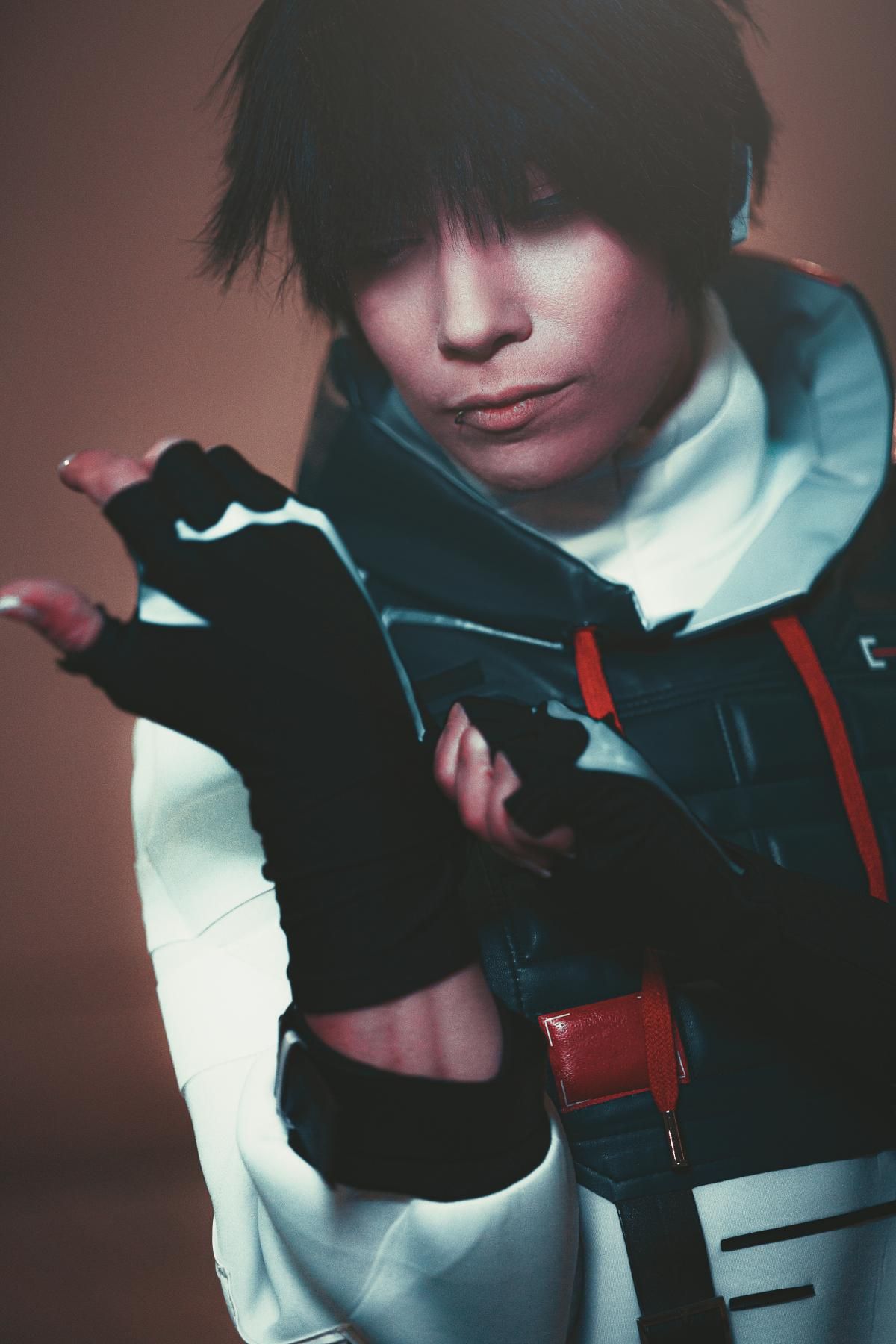 Indoor moody portrait of @Kijou in full ISO top set, showcasing black fingerless tactical gloves with grey segmented armor print, layered high-neck inner mock and vest red drawcord detailing