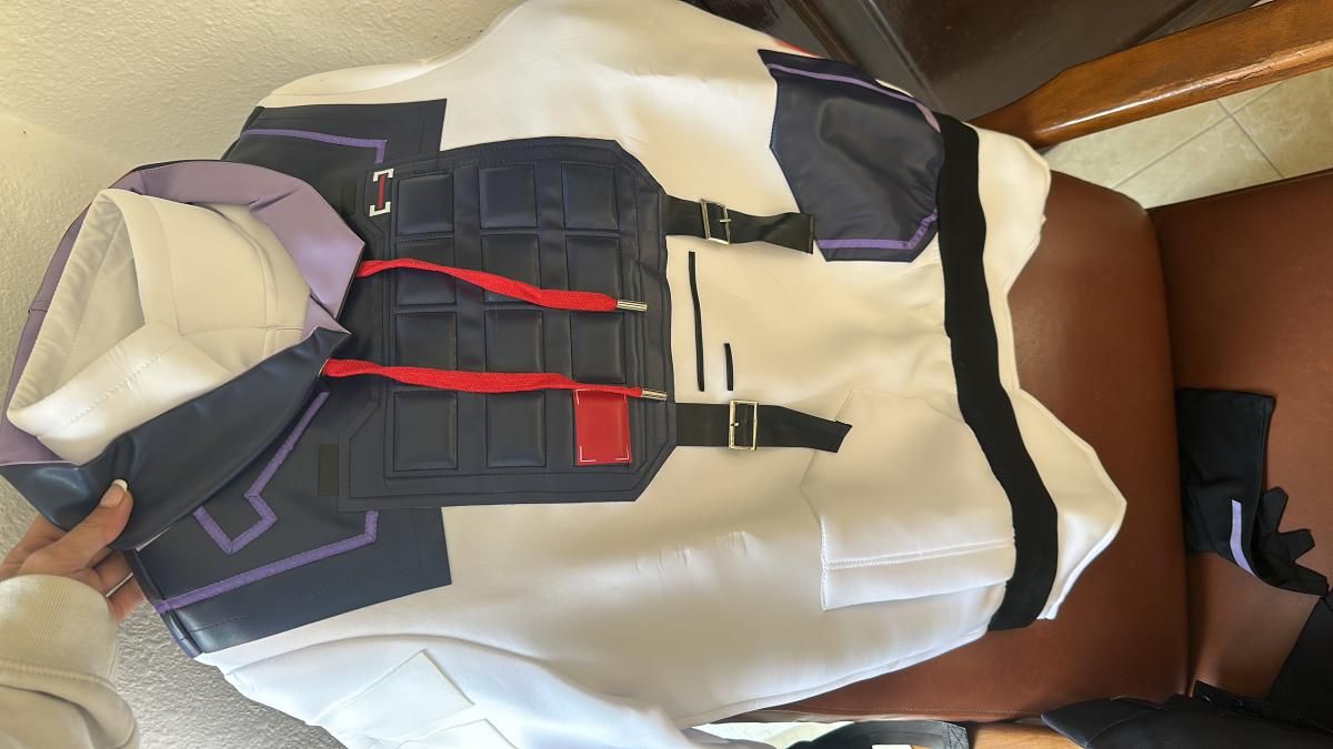 Unbox flat lay shot by buyer @Kijou, white oversized hoodie integrated with dark navy tactical vest overlay, showing embossed armor panel, red drawcords, adjustable black buckle straps and purple piping trim details