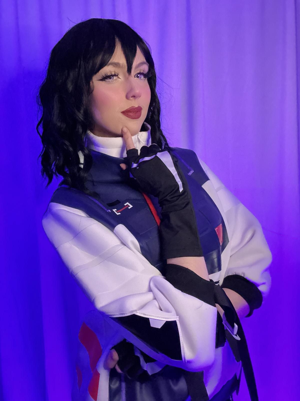 Side profile close-up studio portrait of @susbaddie resting chin on gloved fingertips, highlighting layered mock neck inner shirt, vest piping trim and glove segmented armor print details