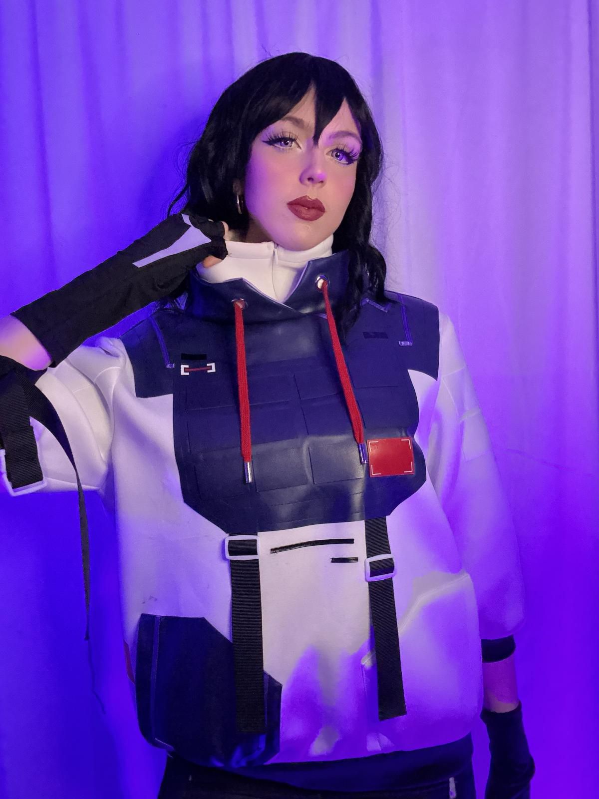 Front-facing studio detail shot of @susbaddie showcasing the full vest armor embossing, dual red drawcords, adjustable chest buckle straps and rectangular red chest accent patch